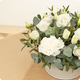 Arrangement floral Nacre avec lisianthus blancs, œillets blancs et eucalyptus dans contenant blanc