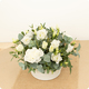 Arrangement floral Nacre avec lisianthus blancs, œillets blancs et eucalyptus dans contenant blanc