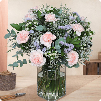 Photo du Bouquet Bienvenue – bouquet rond aux œillets roses, statice lavande, limonium et feuillage vert élégant dans un vase.