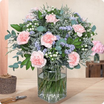Photo du Bouquet Bienvenue – bouquet rond aux œillets roses, statice lavande, limonium et feuillage vert élégant dans un vase.