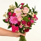 Bouquet de saison rond aux tons roses et fuchsia avec feuillage vert dans un vase en verre
