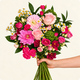 Bouquet de saison rond aux tons roses et fuchsia avec feuillage vert dans un vase en verre