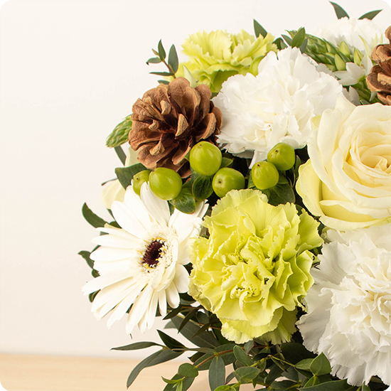 Bouquet rond hivernal blanc et vert avec roses, gerberas et pommes de pin naturelles. Élégance d’hiver. Livraison rapide avec 123fleurs.