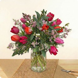 Bouquet rond de tulipes rouges, fuchsia et corail avec feuillage et fleurs de cire