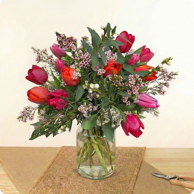 Bouquet rond de tulipes rouges, fuchsia et corail avec feuillage et fleurs de cire