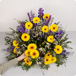 Coussin avec des gerberas et du delphinium dans les tons jaunes et violets