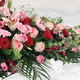 Dessus de cercueil Acerra avec roses rouges, lys roses et feuillage élégant pour cérémonie funéraire - 123fleurs
